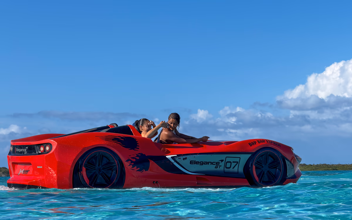 Side view of the red McLaren-styled 2-seater Jet Car on turquoise water, two guests in the seats
