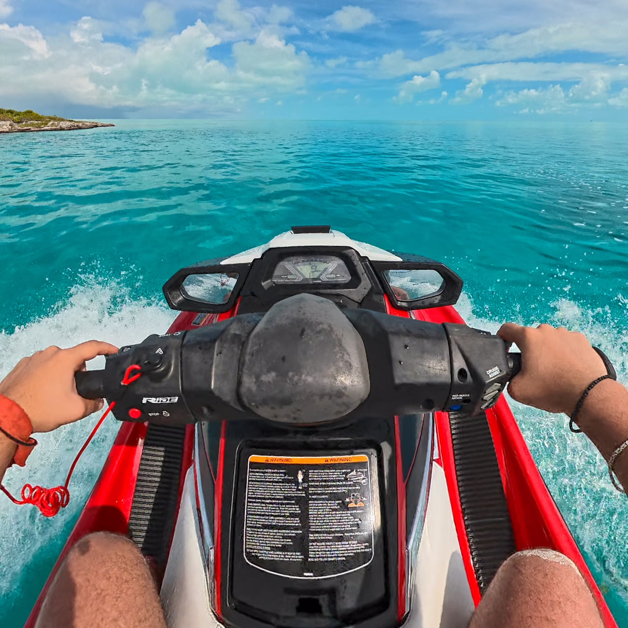 The view over the handlebars of a red and white Yamaha WaveRunner underway across turquoise water