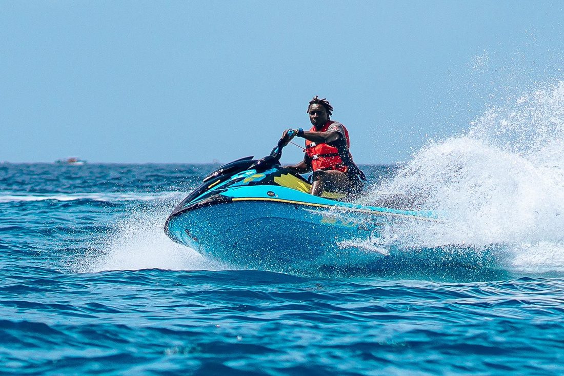 Rider carving a hard turn on a teal Jet Ski, throwing spray