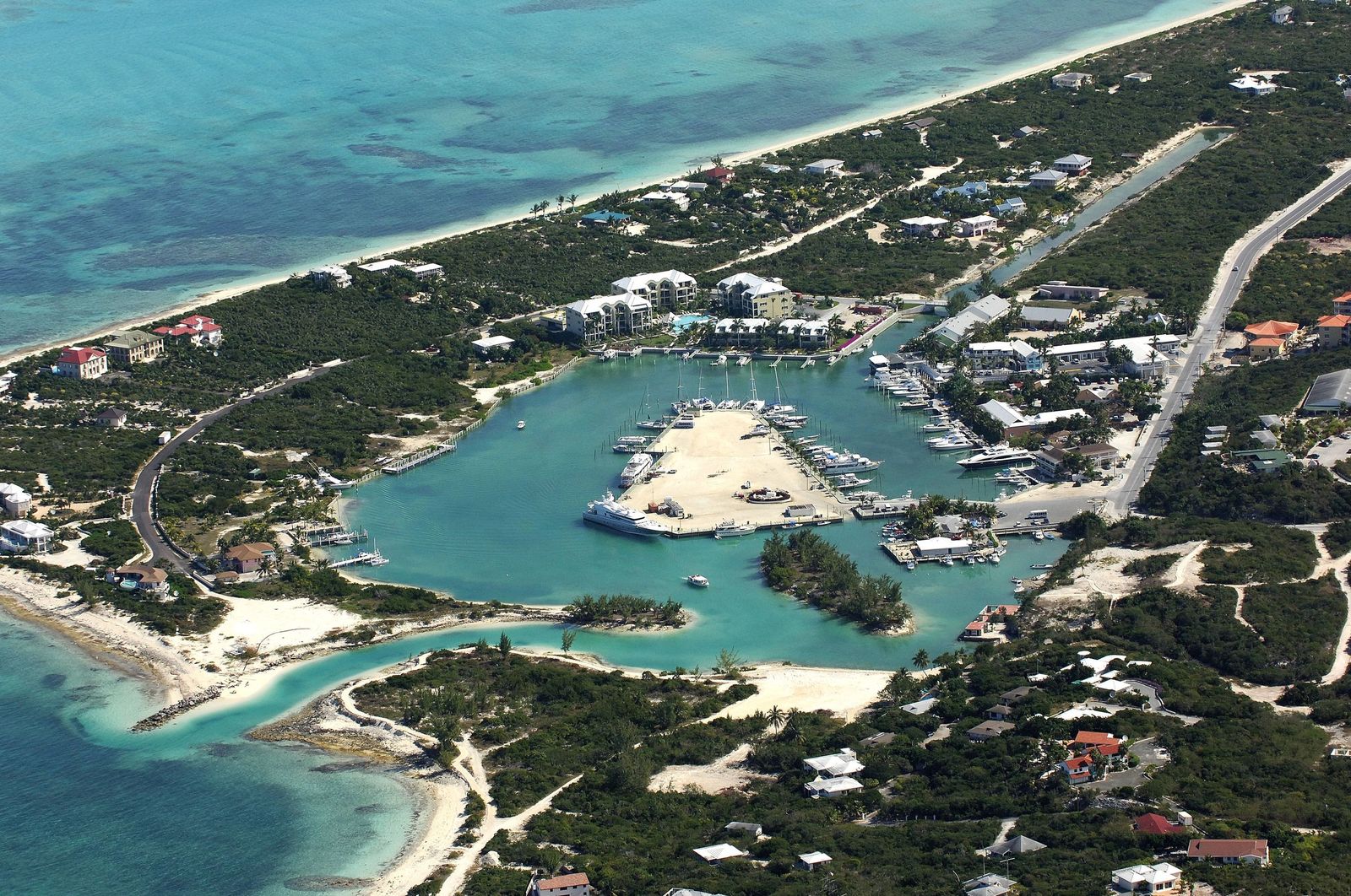 Aerial view of a sheltered harbour on Providenciales, boats along the docks, reef and open water beyond