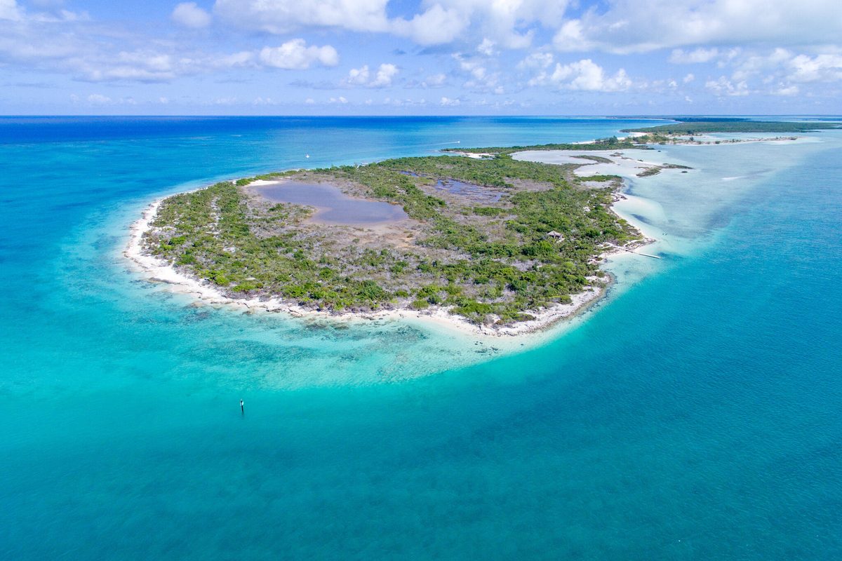 Aerial view of a low green cay ringed by turquoise shallows