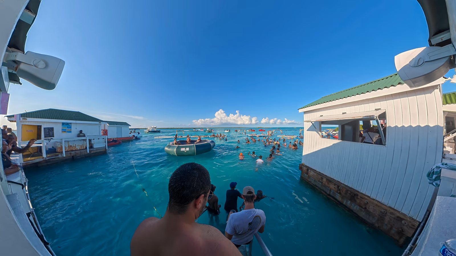 The view from the deck at Noah's Ark over guests in the turquoise shallows, the bar's white buildings on either side