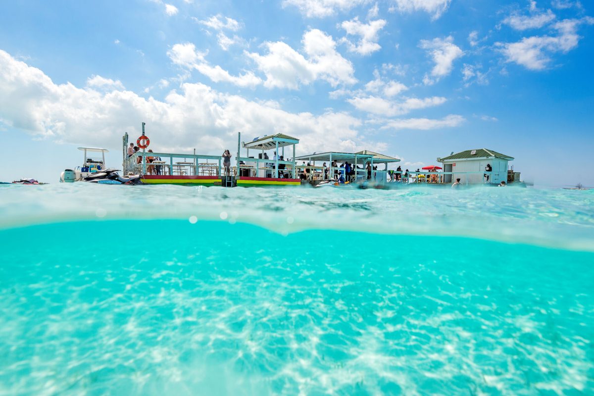 Over-under view of swimmers around the floating tiki bar