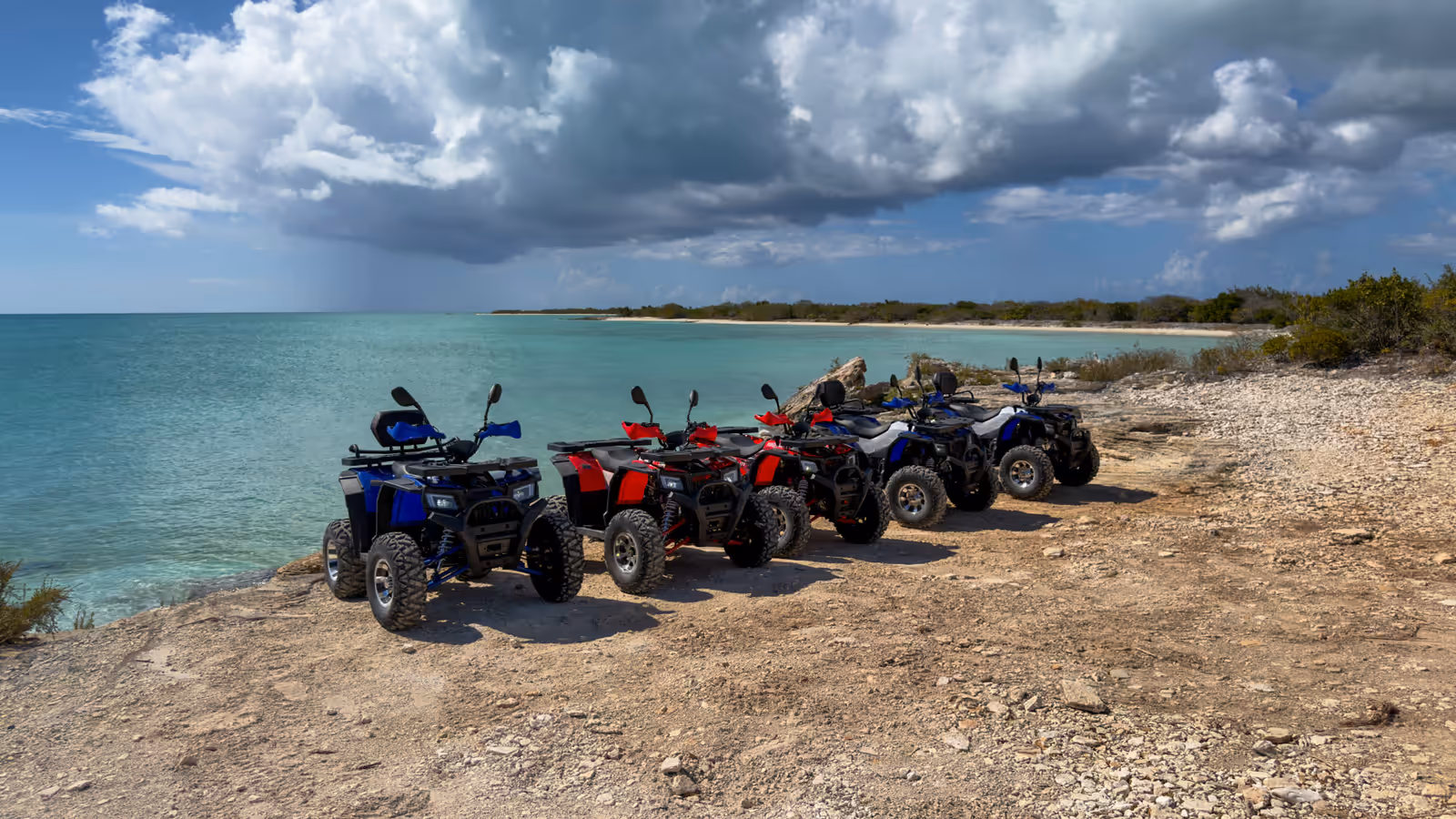 A line of quads parked on the bluff above turquoise water
